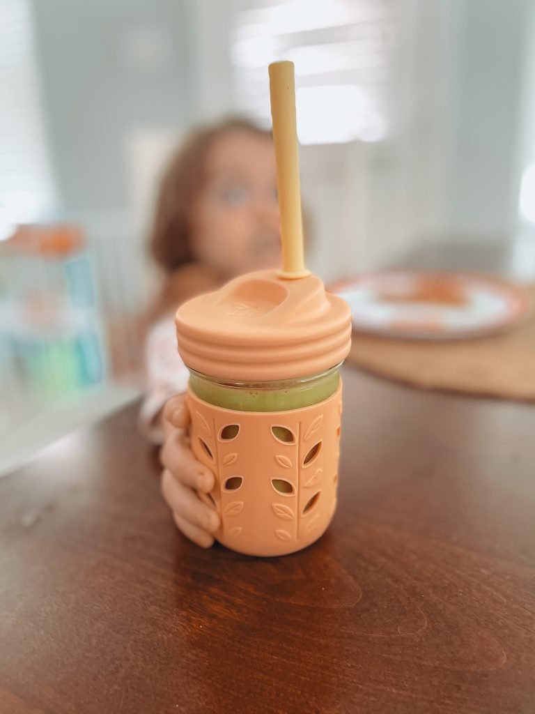 picky toddler holding orange smoothie cup with straw